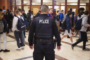 Un oficial de seguridad escolar en South Portland, Maine, se ubica en frente de la oficina principal, mientras los estudiantes se van por el fin de semana, en 2018.