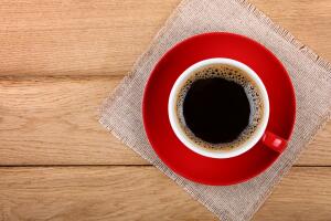 Full cup of black coffee in red cup on table