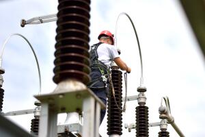 Electrician with Protective Workwear, Hardhat and Safety Harness Working