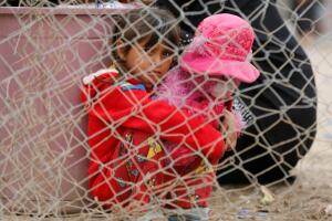 A displaced Iraqi girl who fled home with her family holds her toy upon arrival at Hammam al-Alil camp south of Mosul