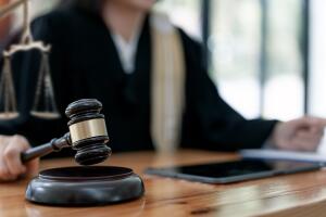 Woman judge hand holding gavel to bang on sounding block in the court room.