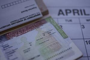 H1B visa stamp in passport, blurred april calendar on background. H1B visa program deadline concept.