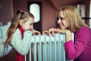 long-haired woman near electric heater at home