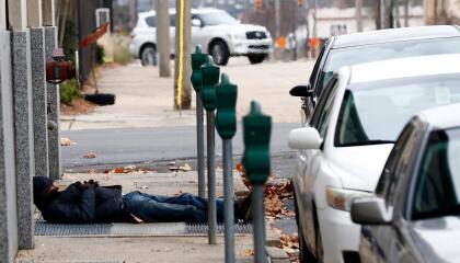 A homeless man takes advantage of the warm air coming from a sidewalk vent to stay warm in downtown Jackson, Miss., Wednesday, Dec. 27, 2017. Weather forecast for central Mississippi calls for freezing or near freezing temperatures at night during the week. (AP Photo/Rogelio V. Solis)