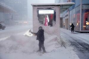 Un hombre palea nieve alrededor de un quiosco durante la tormenta invernal. 