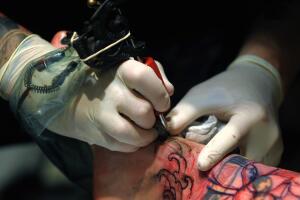 A tattooist works on the leg of a custom