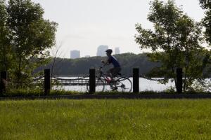 Bicyclist on bike path with Minneapolis skyline.
