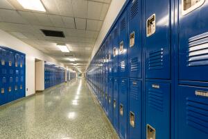 Typical, nondescript USA empty school hallway with royal blue metal lockers along both sides of the hallway.