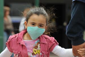 A girl, wearing a mask, holds her father