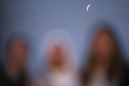 Three woman pose for a picture with the moon in partial eclipse on background in Asuncion's Bay, Paraguay, early Friday, Nov. 19, 2021. (AP Photo/Jorge Saenz)