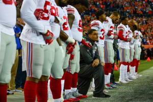 Defensive end Olivier Vernon #54 of the New York Giants, who did not suit up for the game against the Denver Broncos, kneeled on the sideline while teammates locked arms during the national anthem at Sports Authority Field at Mile High on October 15, 2017 in Denver, Colorado