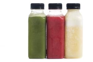 Fresh vegetable detox juice on plastic bottle over a white background