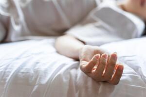 Woman committing suicide in bed, focus on the hand of dead body. The concept of die alone.