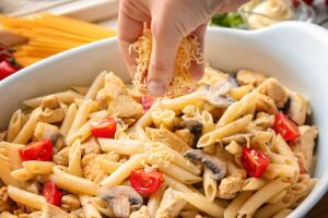 Hand of woman cooking delicious turkey tetrazzini in kitchen