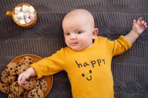 Funny Baby Boy Lying On Knit Plaid With Cookies And Hot Chocolate.