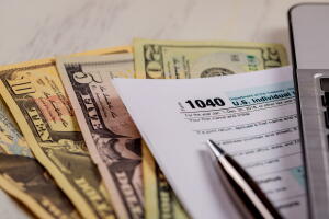 1040 tax form, laptop keyboard and american dollars