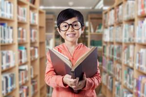 Nino con libro en biblioteca