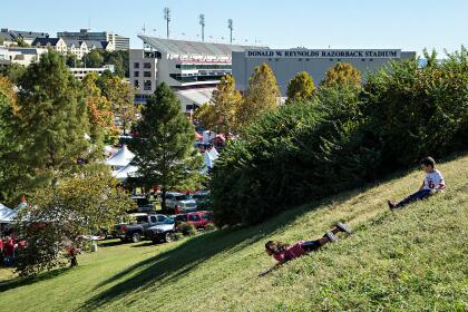 FAYETTEVILLE, AR - OCTOBER 8: Kids slide down a grassy hill in view of the stadium before a game between the Arkansas Razorbacks and the Alabama Crimson Tide at Razorback Stadium on October 8, 2016 in Fayetteville, Arkansas. (Photo by Wesley Hitt/Getty Images)