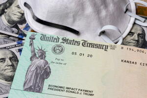 Stimulus check, economic impact payment from Treasury department. 100 dollar bills and n95 respirator mask. Concept of financial hardship, unemployment and recession during Covid-19 coronavirus pandemic