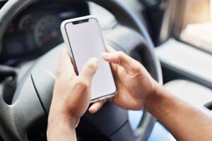 Closeup shot of an unrecognisable delivery man using a cellphone while driving in a car