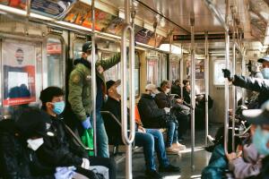 NYC commuters wear protective masks and gloves while riding the subway.