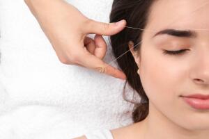 Young woman having professional eyebrow correction procedure in beauty salon, closeup 