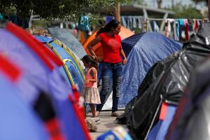 Central American migrants are seen outside their tents in an encampment in Matamoros