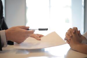 Alguien ofreciendo un lapicero para firmar un papel