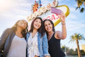all girl group of friends having fun taking selfies in front of welcome to las vegas sign