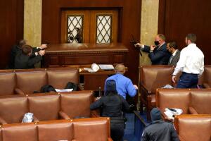 Policías apuntan sus armas a una puerta de la Cámara de Representantes durante una sesión bicameral del Congreso el 6 de enero del 2021.