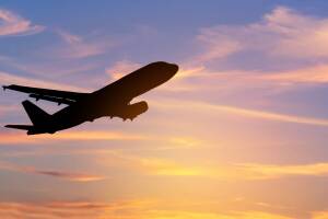   Silhouette passenger airplane flying away in to sky high altitude on sunset