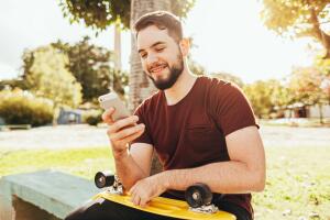 Young skater man using smartphone in the park