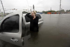 Una mujer habla por teléfono con los servicios de emergencia la mañana del 28 de agosto, tras quedar atrapada entre las aguas con su vehículo en Houston.