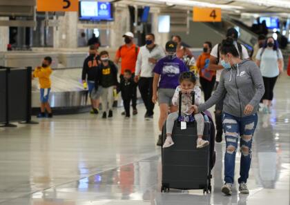 Travelers wear face coverings after gathering their belongings at baggage carousels in the main terminal of Denver International Airport, Tuesday, Aug. 24, 2021, in Denver. (AP Photo/David Zalubowski)
