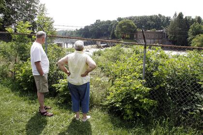 MARSHALL, MI - JULY 28: A couple watches as workers clean up an oil spill of approximately 800,000 gallons of crude from the Kalamazoo River July 28, 2010 in Marshall, Michigan. A 30 inch-wide underground pipeline owned by Calgary, Alberta-based Enbridge Energy Partners LP, began leaking on June 26. (Photo by Bill Pugliano/Getty Images)