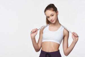 Teen girl measuring her waist with a measuring tape