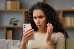 Mujer viendo desconcertada su teléfono celular