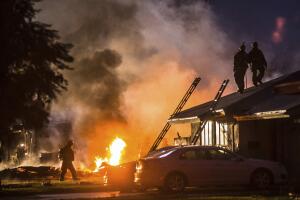 Los bomberos trabajan en la extición del incendio y al búsqueda de víctima en el accidente de una avioneta en un barrio residencial de Riverside. Dos casas quedaron destrozadas.