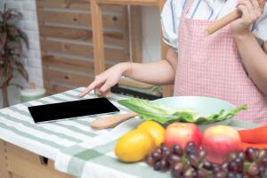Closeup of human hands cooking in kitchen using touch pad. Healt