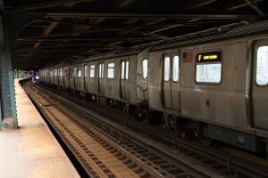 New York City subway train going through the station. F train to Coney Island.  Standing on platform of New York underground train station.  New York public transportation late at night.