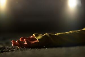 Bloody female victim of deadly car accident lying on road, close-up view at body