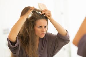 Concerned young woman combing hair in bathroom
