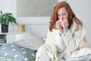 Miserable woman blowing runny nose 