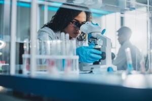 Medical Science Laboratory: Portrait of Beautiful Black Scientist Looking Under Microscope Does Analysis of Test Sample. Ambitious Young Biotechnology Specialist, working with Advanced Equipment