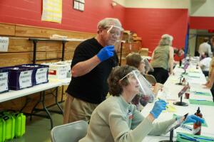 Poll workers are seen wearing face shields and hand gloves