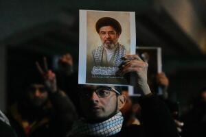 Iraquíes sostienen un retrato del nuevo sucesor del Líder Supremo, el ayatolá Mojtaba Jamenei, en un puente que conduce a la Zona Verde fortificada donde se encuentra la embajada de Estados Unidos en Bagdad. 
