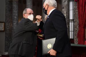 El vicepresidente Mike Pence y el senador republicano por Idaho James Risch se "dan el codo", tras la juramentación en el primer día del nuevo Senado.