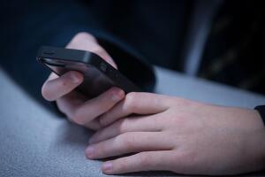 Joven escribiendo en su teléfono celular.