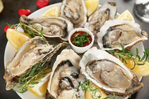 Tasty fresh oysters with sauce and sliced lemon on plate. Aphrodisiac food for increasing sexual desire 