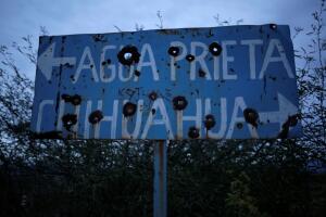 A bullet riddled sign is pictured at a dirt road in Bavispe